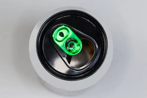 Stock image Used open empty aluminum beverage can with black top and green pull tab on a gray background, top view