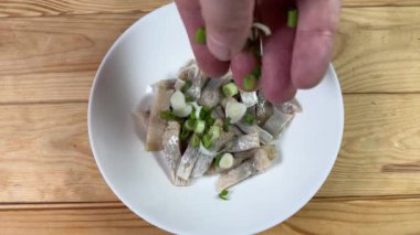 Dilimlenmiş turşu ve yeşil soğanlı ringa balığı.