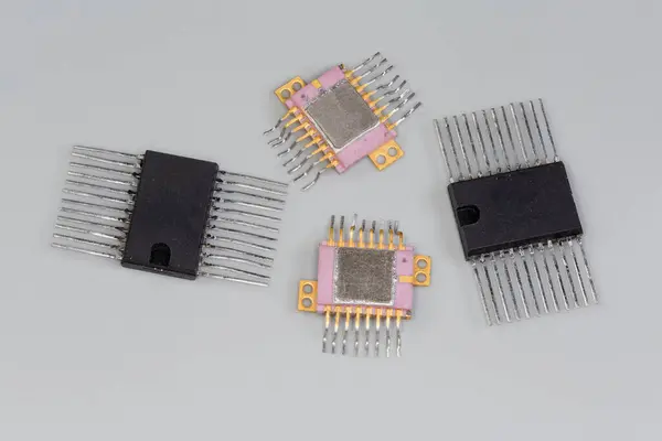 stock image Integrated circuits in the plastic and metal-ceramic rectangular packages with dual-side planar pins for surface mount on printed circuit board close-up on a gray surface