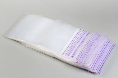 Pahalı olmayan plastik dikdörtgen şeffaf fermuarlı zip kilit çantalarının içinde gri arka planda sürgüsüz mekanizma var.