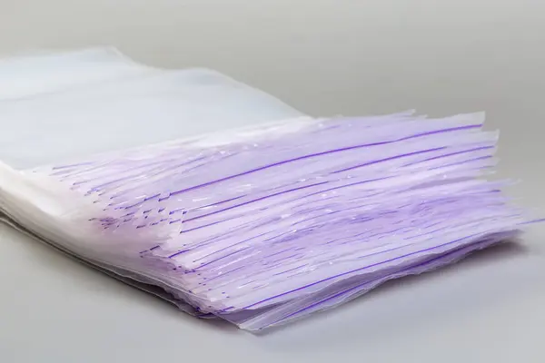 stock image Stack of the inexpensive plastic rectangular transparent reclosable zip lock storage bags with mechanical sealing mechanism without slider on a gray background, close-up in selective focus