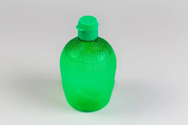 stock image Concentrated lime juice in green plastic container with closed dosing cap on a gray background