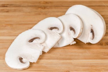 Kısmen dilimlenmiş taze mantar. Ahşap kesme tahtasına yakın plan kesilmiş.