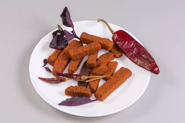 Farklı kurutulmuş acı biber kabukları arasında kahverengi ekmekten yapılmış baharatlı sert ruslar ve gri arka planda taze mor fesleğen yaprakları.