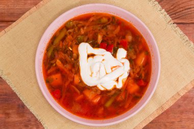 Tipik kırmızı pancar pancarı servis ediliyor Ukrayna borşuna baharatlı ekşi krema ile servis edilmiş tekstil yerinde bir kırsal masa, üst manzara