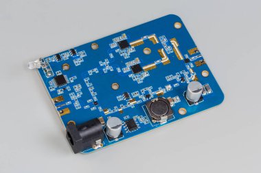 Mavi baskılı devre kartına monte edilmiş mikroçipler ve pasif elektronik parçalarla birleştirilmiş küçük elektronik birim, seçici odak noktasında yakın plan.