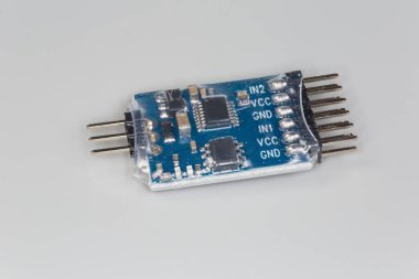 Mavi baskılı devre kartına monte edilmiş mikroçipler ve pasif elektronik bileşenlerle birleştirilmiş küçük elektronik birim. Gri arka planda sıra bağlantıları var.