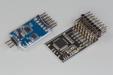 İki farklı küçük elektronik birim, mikro çipler ve pasif bileşenlerle birleştirilmiş. Basılı devre kartına monte edilmiş. Gri arka planda sıra konnektörleri var.