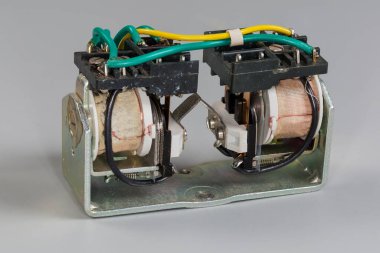 Old electromechanical latching relay, or bistable relay with two coils on a gray background clipart