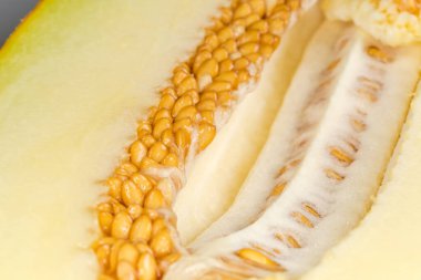 Olgun taze sarı kavunun içi yarısı çekirdek ve hamurla dolu, seçici odak noktasında kesilip, parçalanmış.