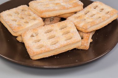 Düz, dikdörtgen, çıtır çıtır kurabiyeler, kabarık hamur işlerinden yapılmış, kahverengi bir çanağa şeker serpiştirilmiş, seçici bir odak noktasında yakın plan.