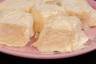 Geleneksel Türk tatlıları, seçici bir odak noktasında, pembe bir tabakta çekilen şekerli un parçalarından oluşan ezilmiş diş ipi şeklinde pislikler.