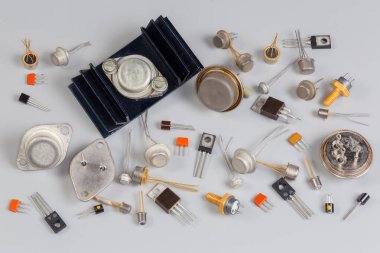 Gri bir yüzey üzerinde değişik metal, seramik ve plastik paketlerde çeşitli amaçlarla eski bipolar ve alan efektli transistörler