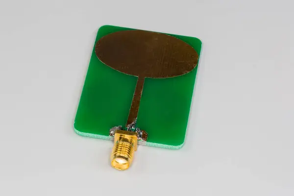 stock image Small-sized flat antenna of high-frequency mobile electronic unit made on the printed circuit board with coaxial connector on a gray background