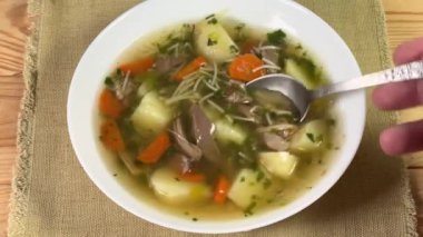 Kaşık ile beyaz kase içinde tavuk çorbası.