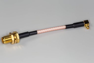 Yüksek frekanslı kablo adaptörü, bir kablo kenarı üzerinde düz eksensel eşeksenli konnektör, diğer kenarı gri bir yüzeyde dik açılı konnektör.