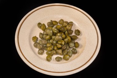 Turşu turşusu, kristalize edilmiş beyaz beneklerle kaplanmış siyah arka planda bir fincan altlığı üzerinde rutin.