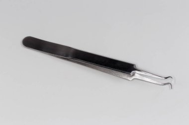 Gri arka planda düz kolları ve kıvrımlı uçları olan geleneksel çelik cımbızlar.