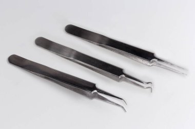 Gri arka planda düz ve kıvrımlı sivri uçlu basit çelik cımbızlar.