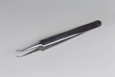 Gri arka planda düz kolları ve kıvrımlı uçları olan geleneksel çelik cımbızlar.