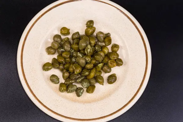 Turşu turşusu, kristalize edilmiş beyaz beneklerle kaplı bir fincan tabağı üzerinde, siyah arka planda üst görünüm.