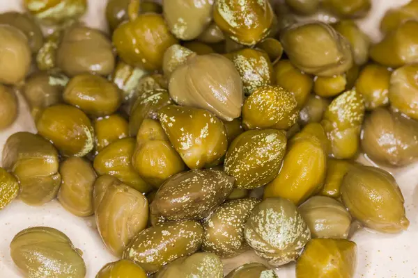 stock image Small heap of pickled capers covered with crystallized white spots of rutin on a saucer, top view close-up in selective focus