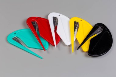Plastik evlerde çelik bıçaklı birkaç güvenlik plastik posta açacağı gri arka planda farklı renkler var.