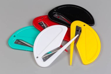 Plastik evlerde çelik bıçaklı birkaç güvenlik plastik posta açacağı gri arka planda farklı renkler var.