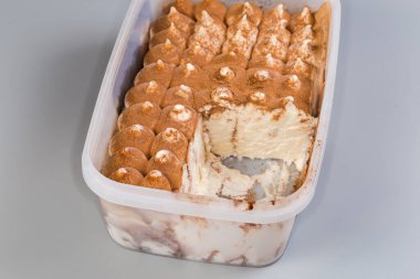 Küresel dondurma parçaları kabın içine kakao tozu serpiştirilmiş kısmen gri arka planda, seçici odak noktasında parçalanmış.