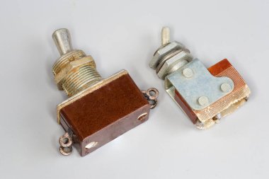 Gri bir arka planda iki eski elektrik düğmesi, farklı bir dizaynı değiştiriyor.