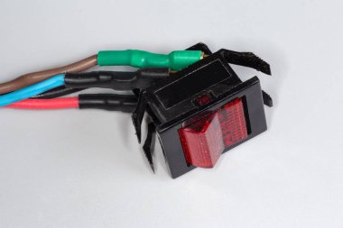 Eski dikdörtgen elektrikli rockçı anahtarı, arka farlı kırmızı anahtar ve elektrik kabloları gri arka plandaki ekipmanı değiştirmek için kullanılıyor.