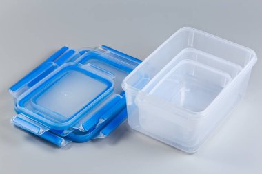 Gri arkaplandaki mavi kapaklı, farklı boyutlarda, yeniden kullanılabilir, saydam plastik gıda saklama kabı seti.