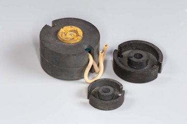 Esrar tipi ferit çekirdekli eski kompakt yüksek frekanslı trafo ve benzer çekirdeklerin yarıları gri bir yüzey üzerindeki değişik mod güç kaynaklarında kullanılıyor.