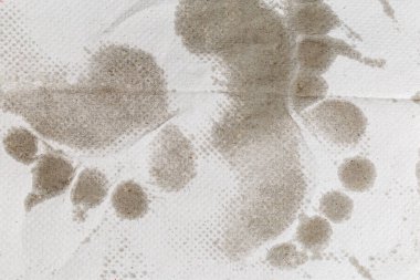 Açık gri, beyazlatılmamış, tek kullanımlık kağıt havlu, ayak parmaklarının ıslak izleri, yakın çekim. 