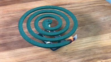 Ahşap yüzeyde dumanı tüten sivrisinek bobini yanıyor ve yanıyor.