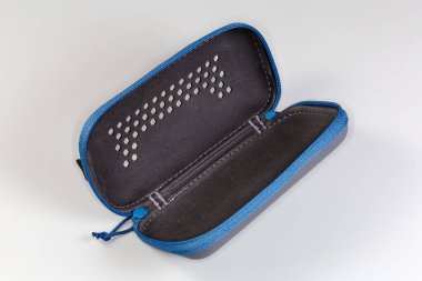 Gri arka planda, üzerinde delikler ve fermuar olan koyu gri, küçük plastik bir çanta aç.