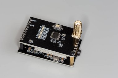 Küçük yüksek frekanslı elektronik ünite, gri arka planda eş eksenli iki siyah baskılı devre kartına monte edilmiş.