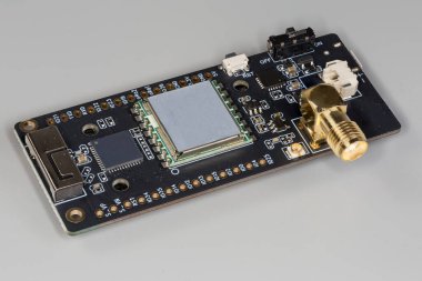 Küçük yüksek frekanslı elektronik ünite, gri arka planda eş eksenli konnektörle birlikte siyah baskılı devre kartının üzerine monte edildi.