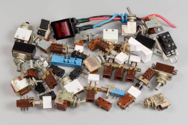 Gri bir arka planda elektrik devrelerini ve güç devrelerini değiştirmek için eski çağdışı elektrik düğmeleri yığını.
