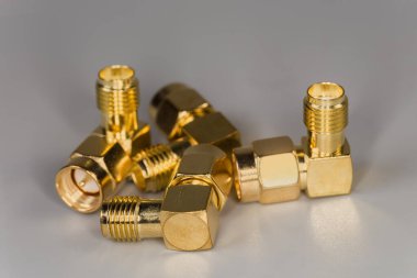 Gri bir yüzey üzerinde erkek ve kadın SMA konnektörleri ile birkaç yüksek frekanslı, sağ açılı, metalik eş eksenli, seçici odak noktasında yakın plan