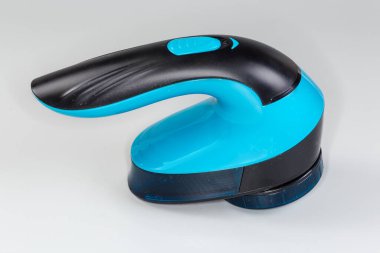 Paslanmaz çelik, dönen bıçak ve gri arka planda bıçak örgüsü olan el bilgisayarı kablosuz kumaş traş makinesi.