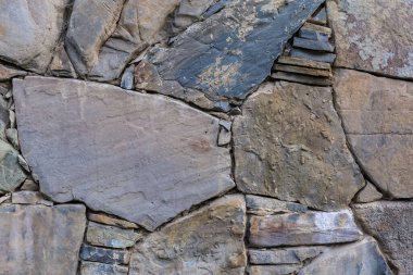 İşlenmemiş düz taşlarla örülmüş engebeli duvarın bir parçası. Bulutlu bir günde farklı şekil ve boyutlarda.