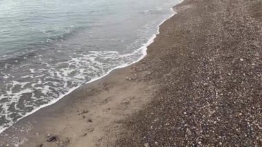 Gökyüzüne ve uzak dağlara karşı deniz kıyısındaki çakıl taşı plajı