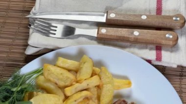 Kızarmış kemiksiz domuz pirzolası, fırında sebze ve patates kızartması.