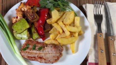 Kızarmış kemiksiz domuz pirzolası, fırında sebze ve patates kızartması.