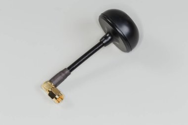 Eşeksen kablosunun kenarında gri bir arka planda eşeksen konnektörü olan yüksek frekanslı mobil elektronik birimin küçük boyutlu yuvarlak anteni.