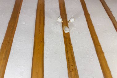 Tavan parçası beyaz desenli alçıyla kaplıydı ve uzaktan sıralanmış verniklenmiş doğal ladin tahtaları yıllık tavan lambası ve belirgin büyüme çizgileri vardı.