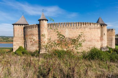 Khotyn fortress of the 14th century at autumn sunny day, Ukraine. View from the west of the defensive walls and towers with dog-rose bush on a foreground clipart