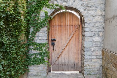 Eski ahşap kale kemerli eski kaba taş duvarın açılması tırmanma bitkileriyle kaplı.