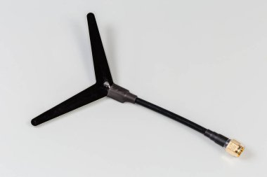 Small-sized flat antenna of high-frequency electronic unit with coaxial connector on the edge of coaxial cable on a gray background clipart